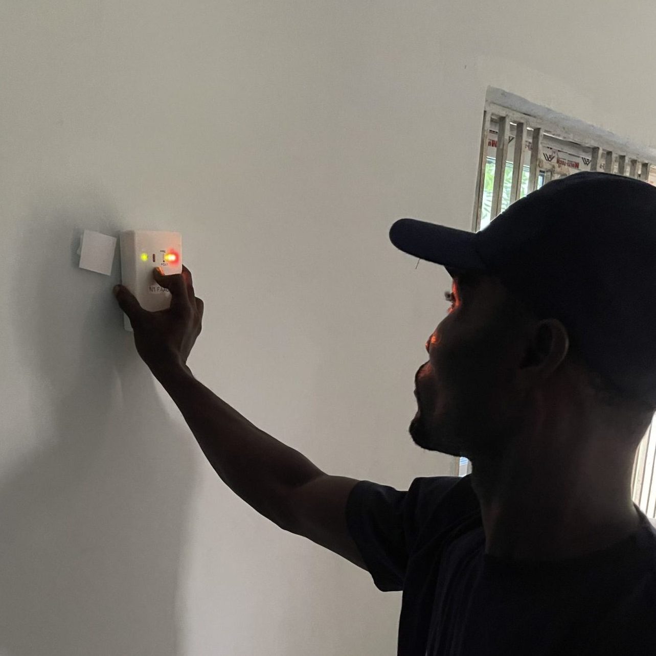Man using a sensor to monitor insecticide on a white wall in a room