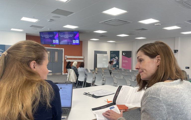 Two senior female members of the iiCON team discussing a pitch event